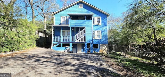 view of front facade featuring fence, asphalt driveway, and a porch