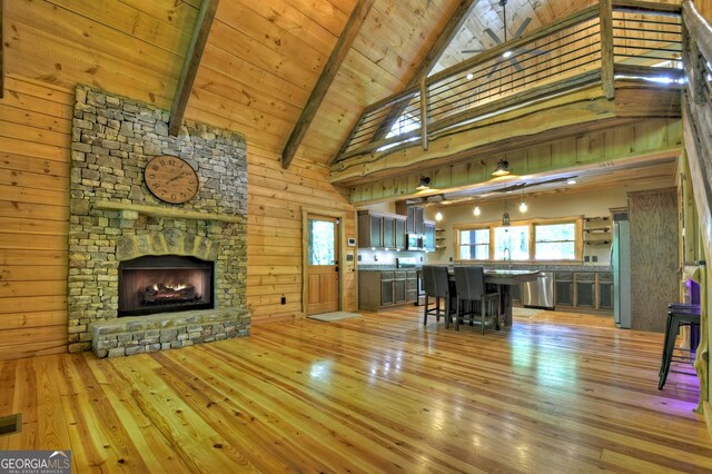 179 Huckleberry Ln, Ellijay, GA 30536 - living room featuring light wood finished floors, beam ceiling, high vaulted ceiling, a stone fireplace, and wood ceiling