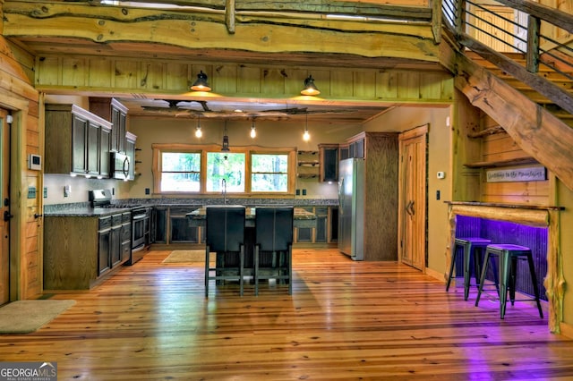 179 Huckleberry Ln, Ellijay, GA 30536 - kitchen featuring appliances with stainless steel finishes, dark countertops, light wood finished floors, a kitchen island, and a kitchen breakfast bar
