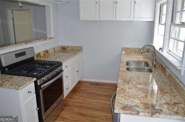2381 Eastway Rd, Decatur, GA 30033 - kitchen featuring gas stove, a sink, light wood finished floors, white cabinets, and plenty of natural light