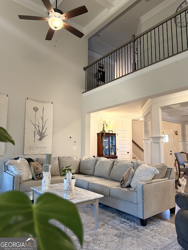 living area with a towering ceiling, a ceiling fan, and stairway