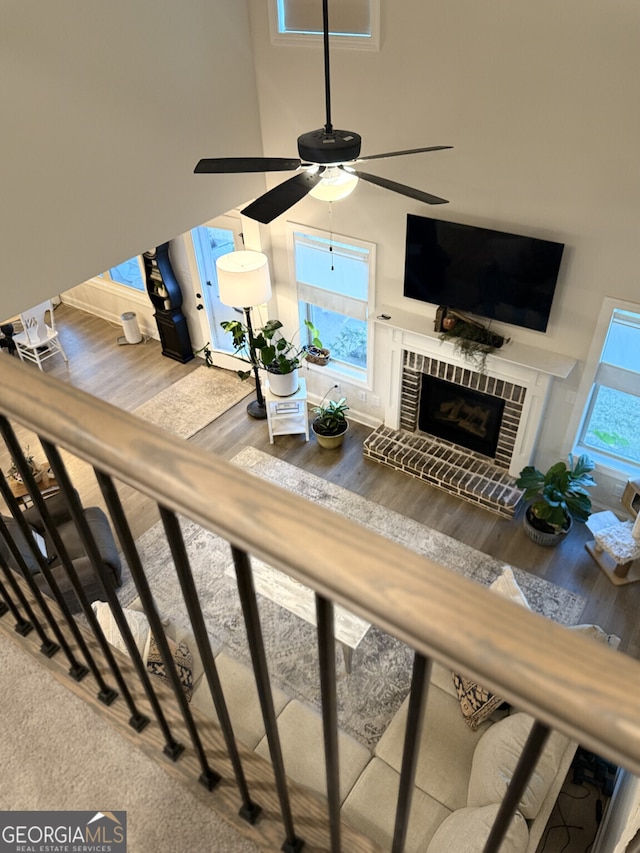 living room featuring wood finished floors, a fireplace, a high ceiling, and a ceiling fan