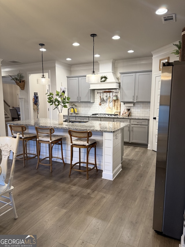 kitchen with ornamental molding, gray cabinetry, stainless steel appliances, premium range hood, and a sink