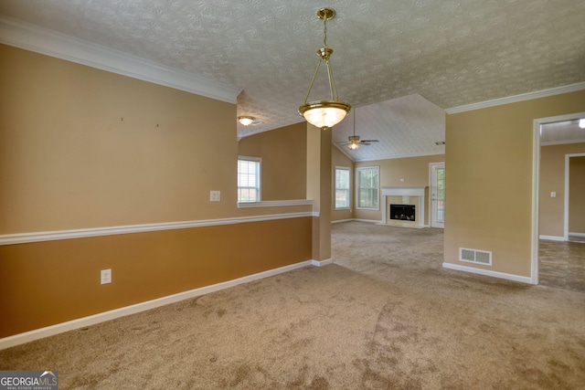 unfurnished living room featuring carpet flooring, ceiling fan, baseboards, a tiled fireplace, and crown molding