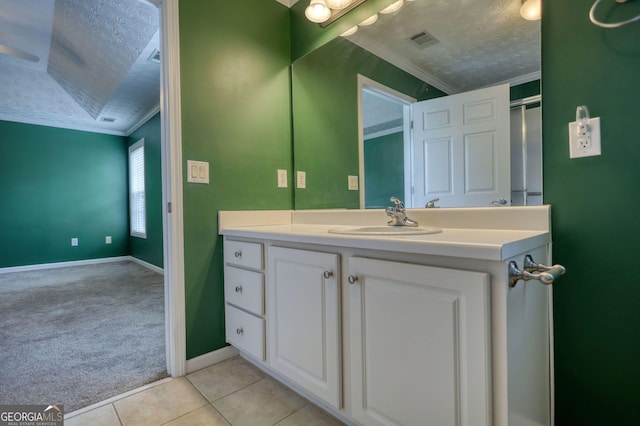 bathroom featuring a textured ceiling, crown molding, tile patterned floors, baseboards, and vanity