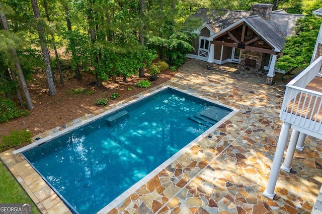 swimming pool with a patio and an exterior structure