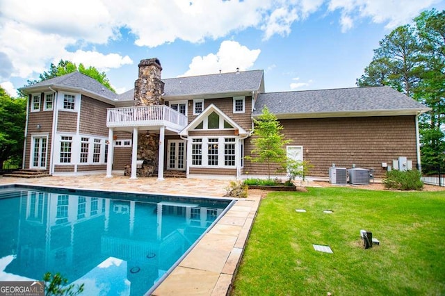 back of house featuring french doors, a lawn, a patio, cooling unit, and an outdoor pool