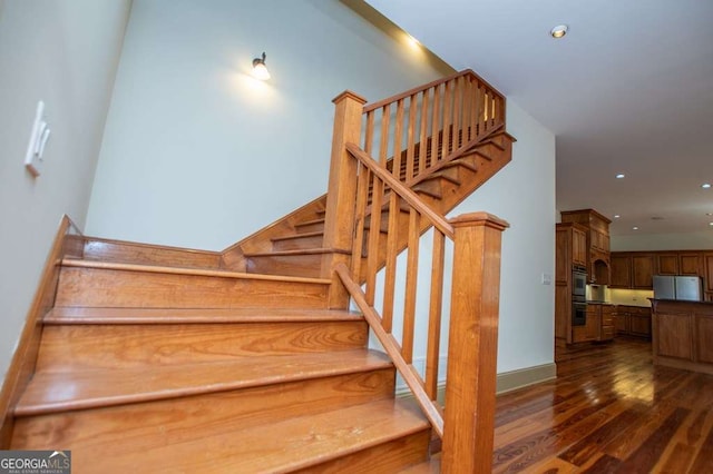 staircase with wood finished floors and recessed lighting