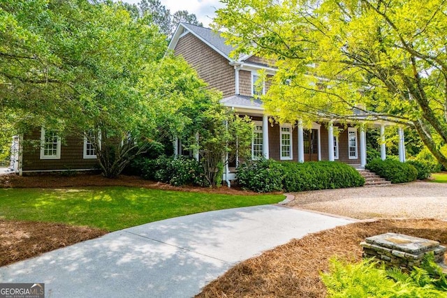 view of property hidden behind natural elements featuring a front yard and a porch