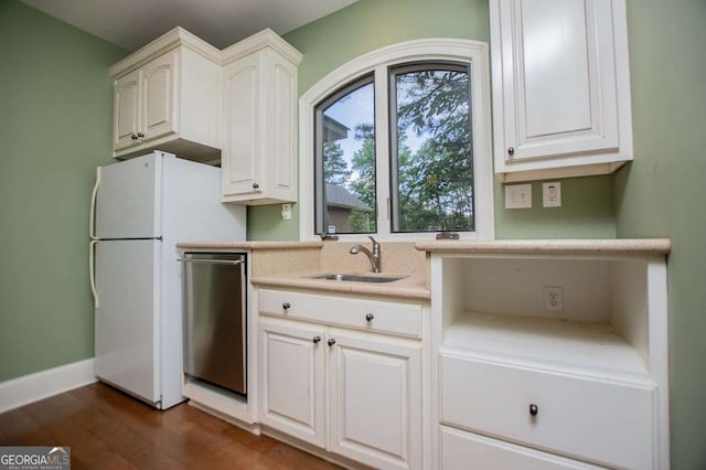 kitchen featuring a sink, dishwasher, light countertops, dark wood-style flooring, and freestanding refrigerator