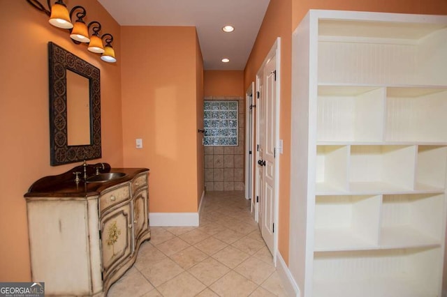 hallway with light tile patterned floors, baseboards, a sink, and recessed lighting