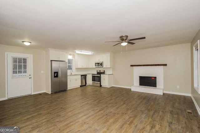 434 Mona Pl, Dallas, GA 30132 - unfurnished living room featuring ceiling fan, dark wood-style floors, baseboards, a sink, and a brick fireplace