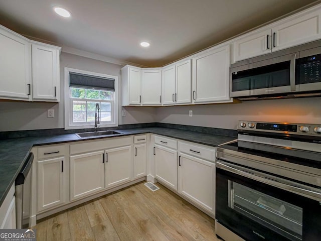 136 Oak St Unit 0, Omega, GA 31775 - kitchen with stainless steel appliances, a sink, light wood-style flooring, white cabinetry, and ornamental molding