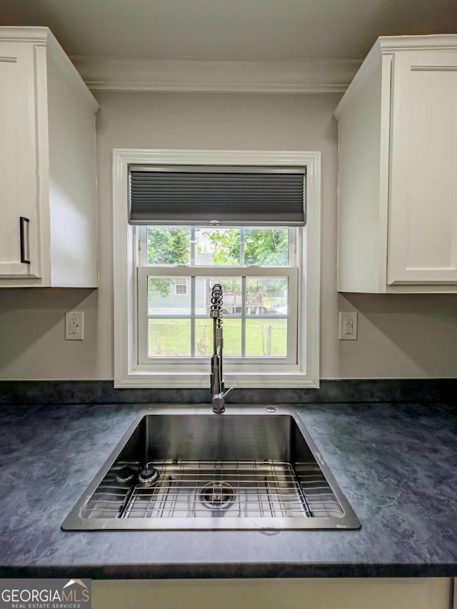 136 Oak St Unit 0, Omega, GA 31775 - kitchen view of dark countertops, a sink, ornamental molding, and white cabinetry
