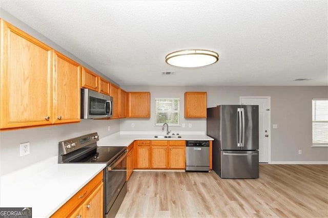 1023 Saint Augustine Pkwy, Locust Grove, GA 30248 - kitchen featuring stainless steel appliances, a sink, light wood finished floors, healthy amount of natural light, and a textured ceiling