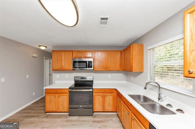 1023 Saint Augustine Pkwy, Locust Grove, GA 30248 - kitchen featuring appliances with stainless steel finishes, a sink, light wood-style flooring, and light countertops
