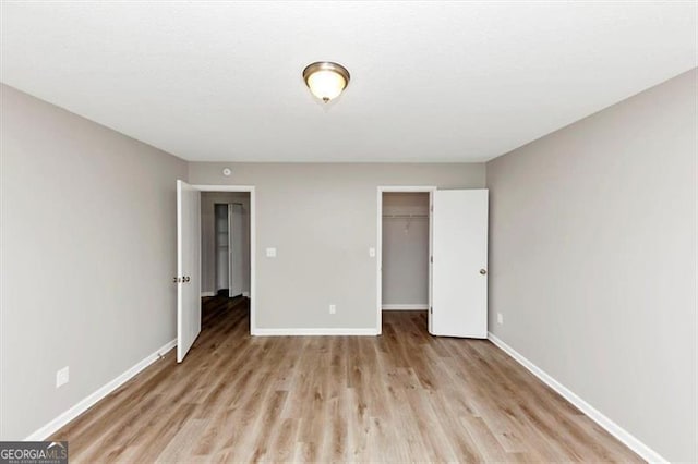 1023 Saint Augustine Pkwy, Locust Grove, GA 30248 - unfurnished bedroom with baseboards, wood finished floors, a closet, and a walk in closet