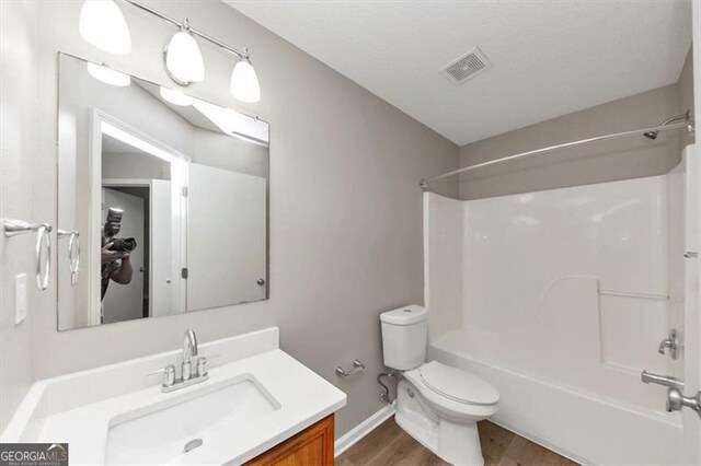 1023 Saint Augustine Pkwy, Locust Grove, GA 30248 - bathroom with wood finished floors, toilet, bathtub / shower combination, vanity, and baseboards