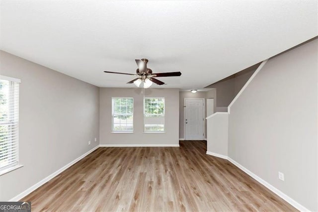 1023 Saint Augustine Pkwy, Locust Grove, GA 30248 - unfurnished living room featuring wood finished floors, baseboards, and ceiling fan