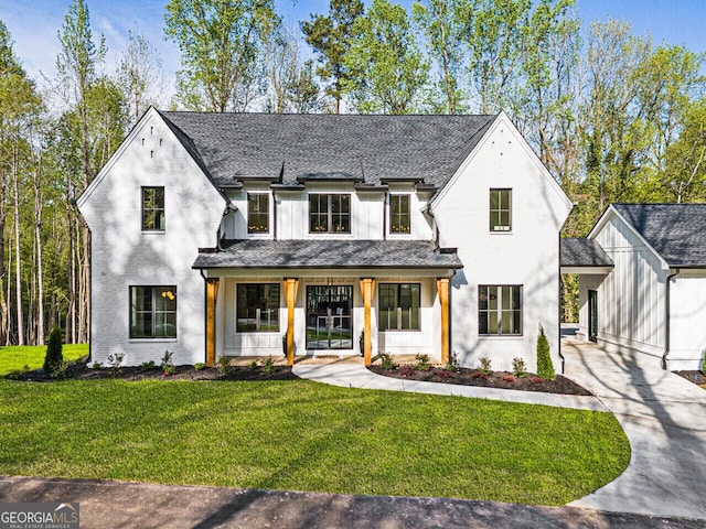 view of front of home with a front lawn, an outdoor structure, driveway, and a shingled roof