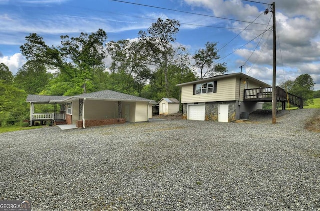 view of home's exterior featuring driveway, a storage unit, an outbuilding, a garage, and a wooden deck
