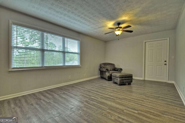 unfurnished room with wood finished floors, plenty of natural light, ceiling fan, baseboards, and a textured ceiling
