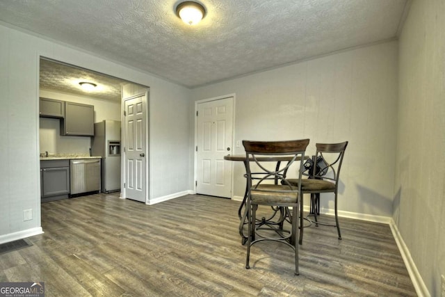 dining room with a textured ceiling, dark wood-style floors, and baseboards