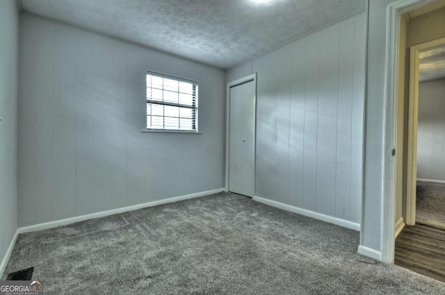 unfurnished bedroom featuring carpet flooring, a closet, a textured ceiling, and baseboards