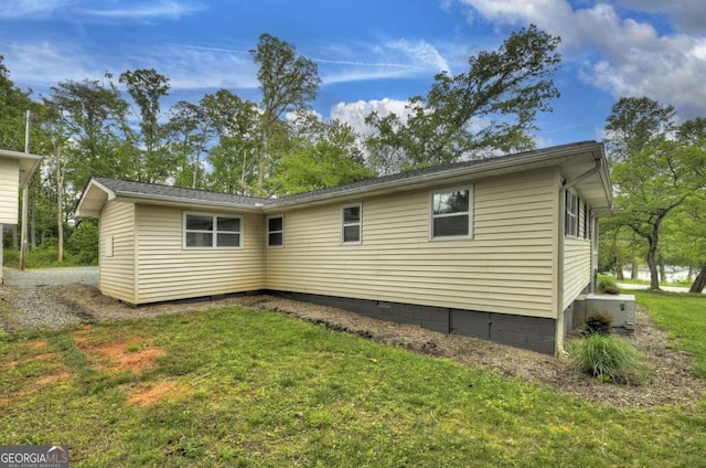 rear view of property with central air condition unit and a lawn
