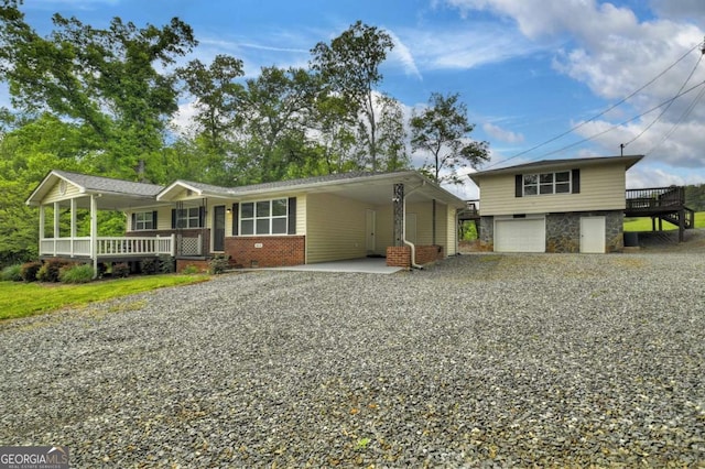 view of front facade with gravel driveway, a garage, covered porch, stone siding, and brick siding