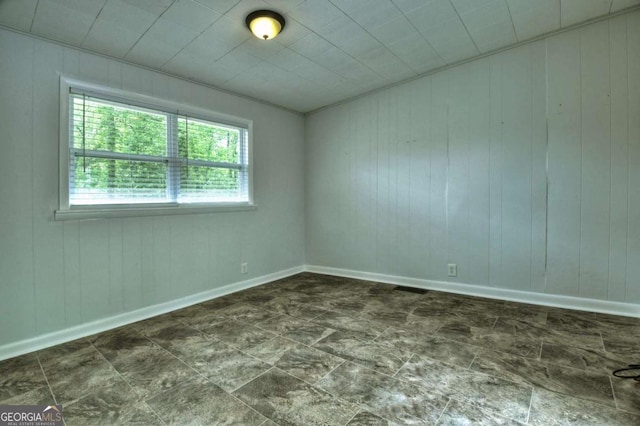 unfurnished room with wooden walls and baseboards