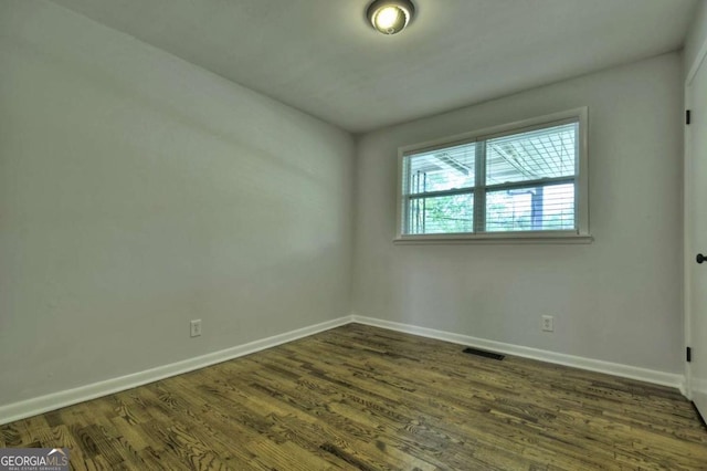unfurnished room with baseboards and dark wood-style floors