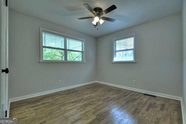 unfurnished room with plenty of natural light, baseboards, dark wood finished floors, and a ceiling fan