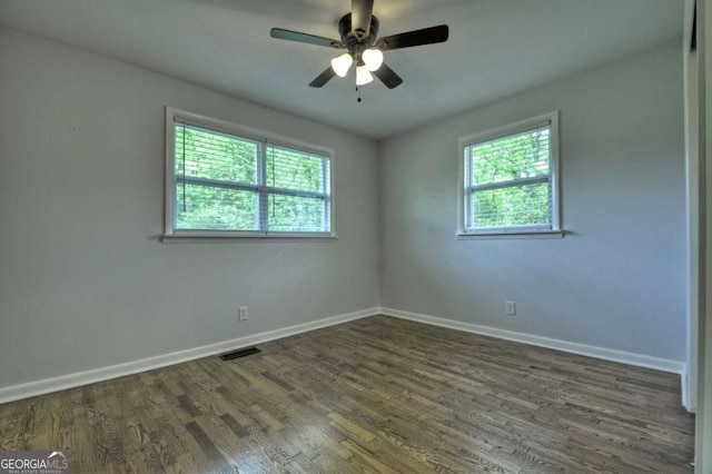 spare room with baseboards, dark wood-style floors, and a ceiling fan