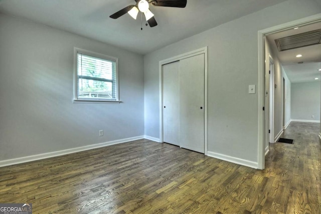 unfurnished bedroom with baseboards, dark wood-type flooring, a closet, and ceiling fan