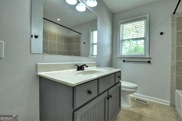 bathroom with vanity, toilet, baseboards, tile patterned floors, and bathtub / shower combination