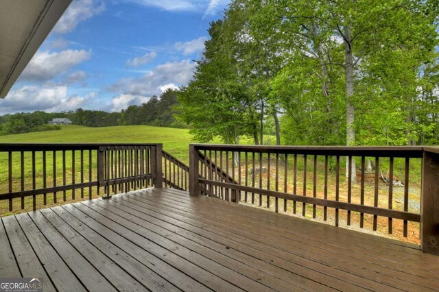 wooden terrace with a yard and view of wooded area