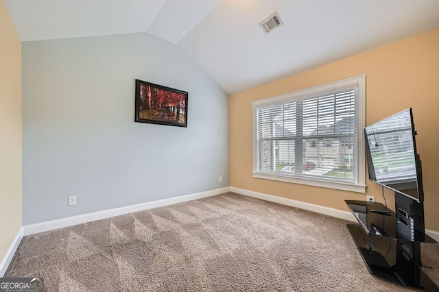 spare room featuring vaulted ceiling, carpet flooring, and baseboards