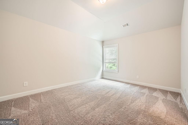 unfurnished room with carpet floors, baseboards, and vaulted ceiling