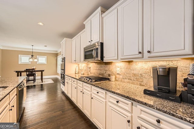 kitchen featuring appliances with stainless steel finishes, baseboards, crown molding, decorative backsplash, and dark stone countertops