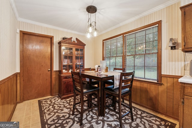 dining area featuring wainscoting, crown molding, wood walls, and wallpapered walls