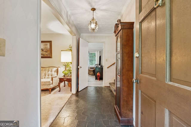 entrance foyer with dark stone finish floors, ornamental molding, a chandelier, baseboards, and stairs