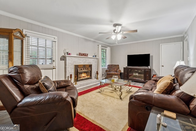 living area with crown molding, ceiling fan, and a brick fireplace