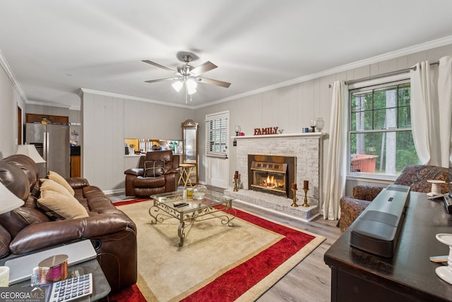 living area with crown molding, a ceiling fan, wood finished floors, and a fireplace