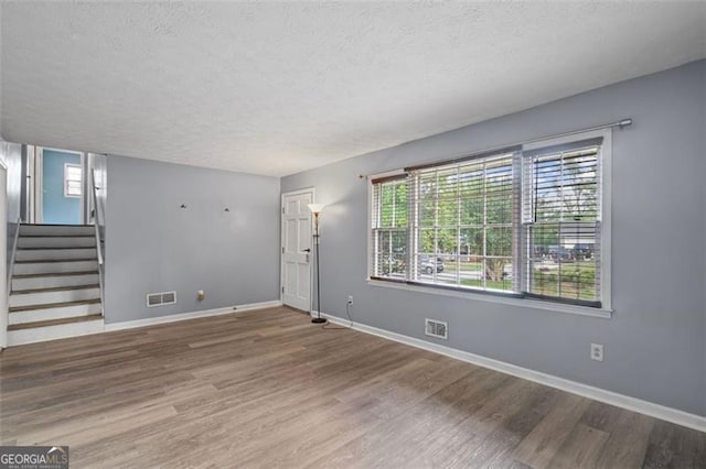 6997 Vesta Brook Dr, Morrow, GA 30260 - unfurnished living room featuring a textured ceiling, wood finished floors, stairway, and baseboards