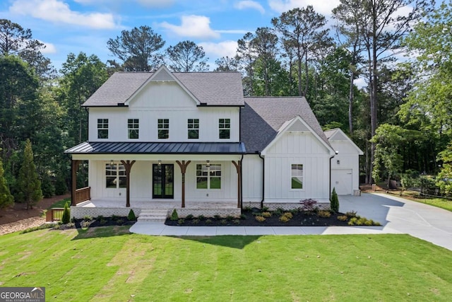 modern inspired farmhouse featuring board and batten siding, a standing seam roof, a porch, concrete driveway, and a front lawn