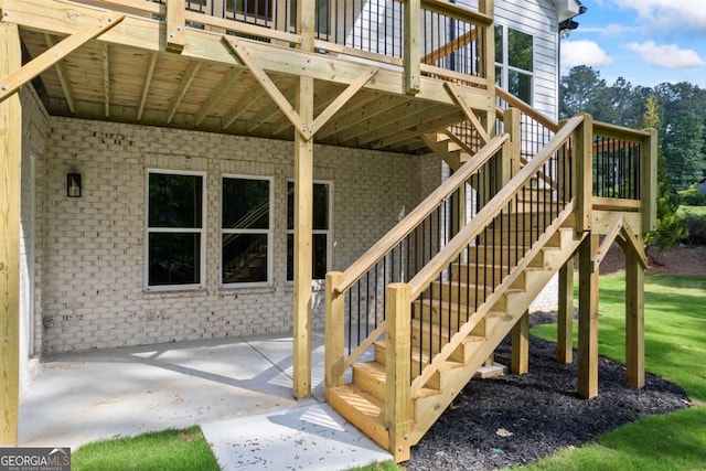 entrance to property featuring a patio area, a deck, and brick siding