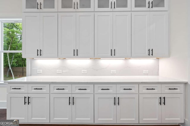 kitchen with white cabinets, backsplash, and glass insert cabinets