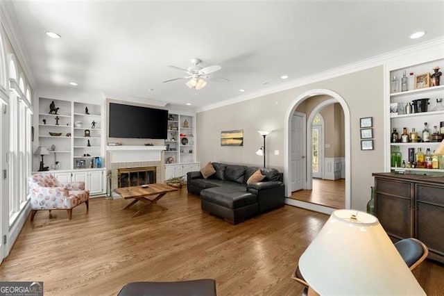 194 Sentinel Pl SE, Marietta, GA 30067 - living room with a ceiling fan, built in shelves, arched walkways, wood finished floors, and crown molding