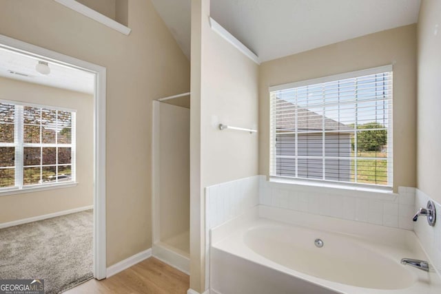 40 Wimberly Way, Covington, GA 30016 - bathroom with a bath, baseboards, a shower, wood finished floors, and vaulted ceiling